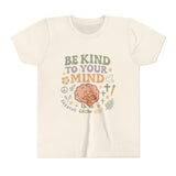 Retro-style t-shirt with “Be Kind to Your Mind” text, featuring a smiling cartoon brain hugging a heart, surrounded by peaceful doodles and affirmations like “Breathe,” “Grow,” and “Rest.”