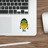 Laptop with a sticker of a yellow character wearing a green hat with 'FAITH' on it, on a wooden desk.