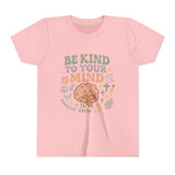 Retro-style t-shirt with “Be Kind to Your Mind” text, featuring a smiling cartoon brain hugging a heart, surrounded by peaceful doodles and affirmations like “Breathe,” “Grow,” and “Rest.”