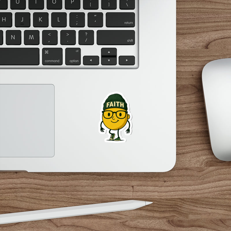 Laptop with a sticker of a yellow character wearing a green hat with 'FAITH' on it, on a wooden desk.