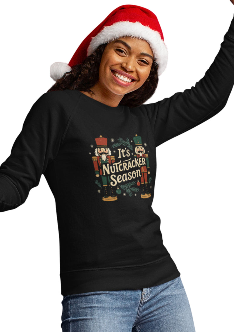 A festive holiday sweatshirt with a colorful nutcracker illustration and the phrase “It’s Nutcracker Season” in bold, cheerful lettering.