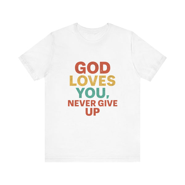Young woman pointing to a bold black t-shirt with the words "God Loves You. Never Give Up," holding a white "Klippette" cap, standing confidently in front of a gate.