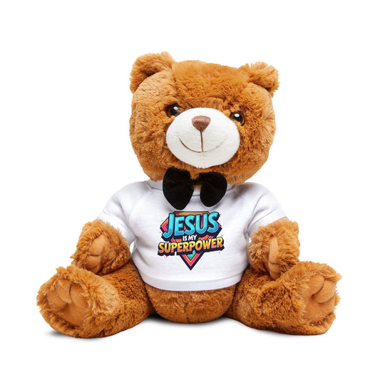 Brown teddy bear wearing a “Jesus is My Super Power” shirt, sitting with a bow tie and a joyful expression